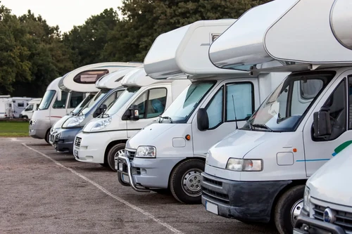 Row of recreational vehicles parked in outdoor storage lot.